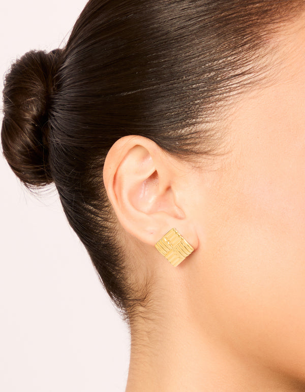 Showcasing waterproof gold plated stainless steel square ribbed stud earrings with statement styling on ear view