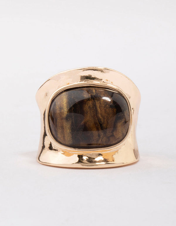 Highlighting a tortoiseshell pattern statement chunky stone band ring in gold close up view