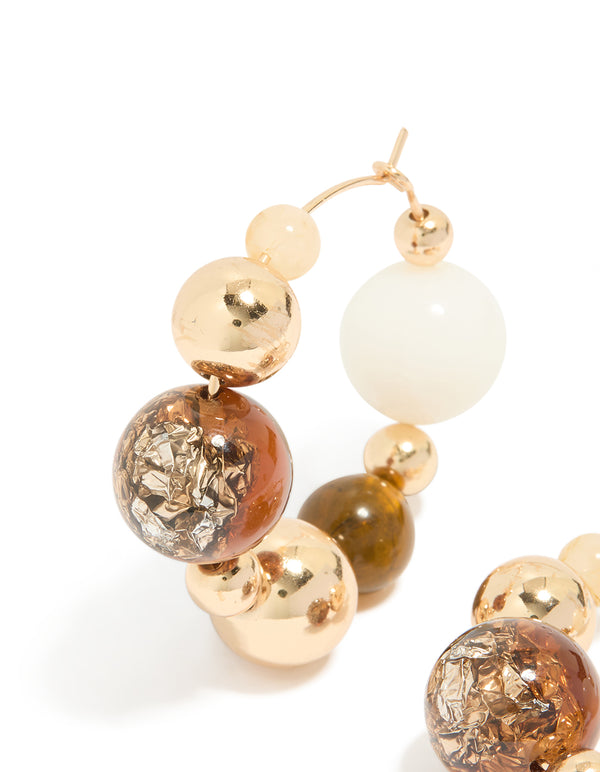 Featuring gold chunky neutral beaded ball hoop earrings with textured details close up view