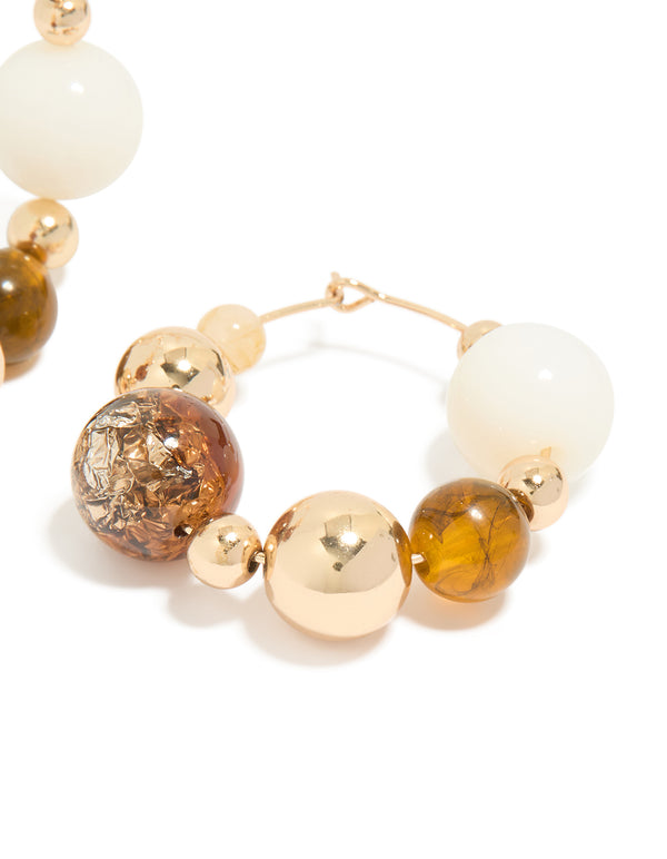 Designed with gold chunky neutral beaded ball hoop earrings highlighting closure mechanism post detail view