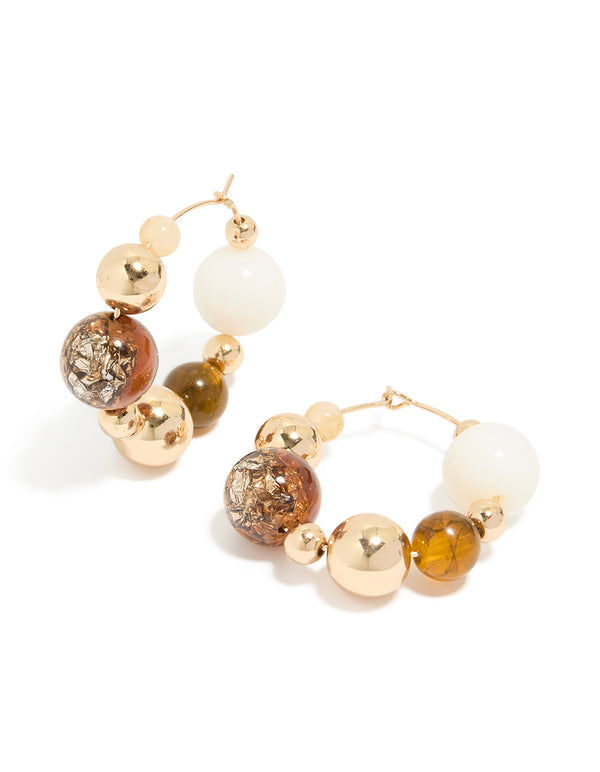 Beautifully designed chunky beaded and ball hoop earrings featuring neutral tones with gold accents front view