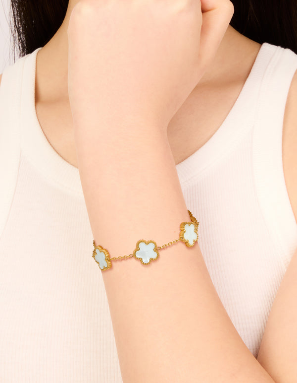 Crafted from waterproof gold plated stainless steel, this flower petal charm bracelet features ivory floral details on wrist view