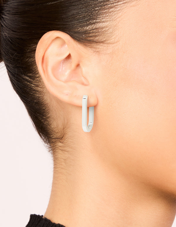 Featuring waterproof stainless steel oblong hoop earrings in silver on ear view