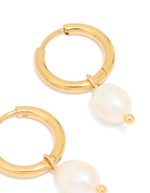 Displayed are waterproof gold plated stainless steel mini pearl drop huggie earrings in ivory close up view