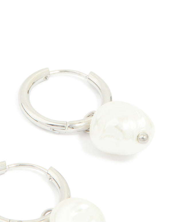 Crafted from waterproof stainless steel, pearl huggie earrings in white and silver post detail view