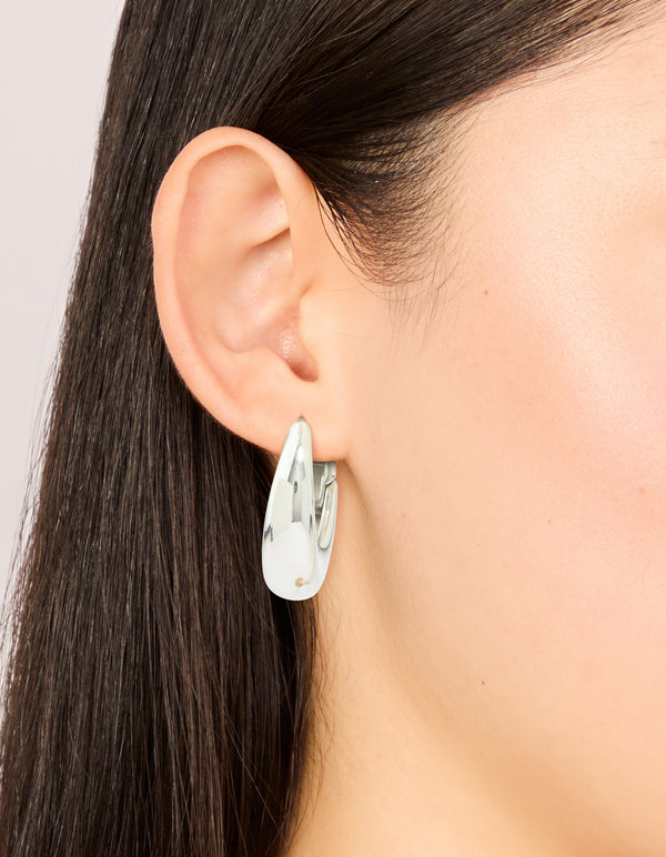 Crafted from waterproof stainless steel, these oval hinged hoop earrings in silver shown on ear view