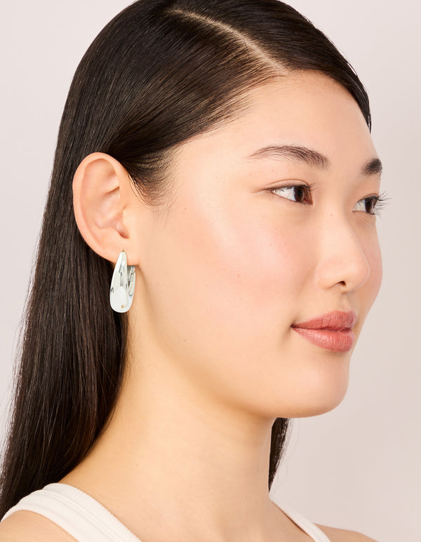 Showcasing waterproof stainless steel oval hinged hoop earrings in silver on model view