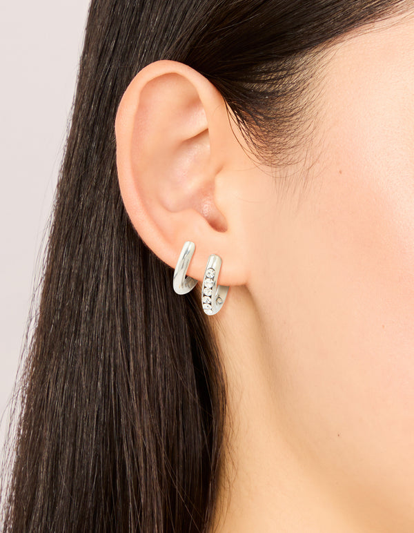 Crafted from waterproof stainless steel, chunky cubic zirconia and smooth huggie earrings 2-pack featuring crystal accents in silver front view