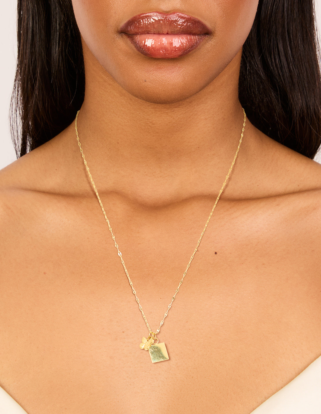 Showcasing a waterproof square and butterfly pendant necklace with charm in dainty style, crafted from stainless steel gold plated on neck view