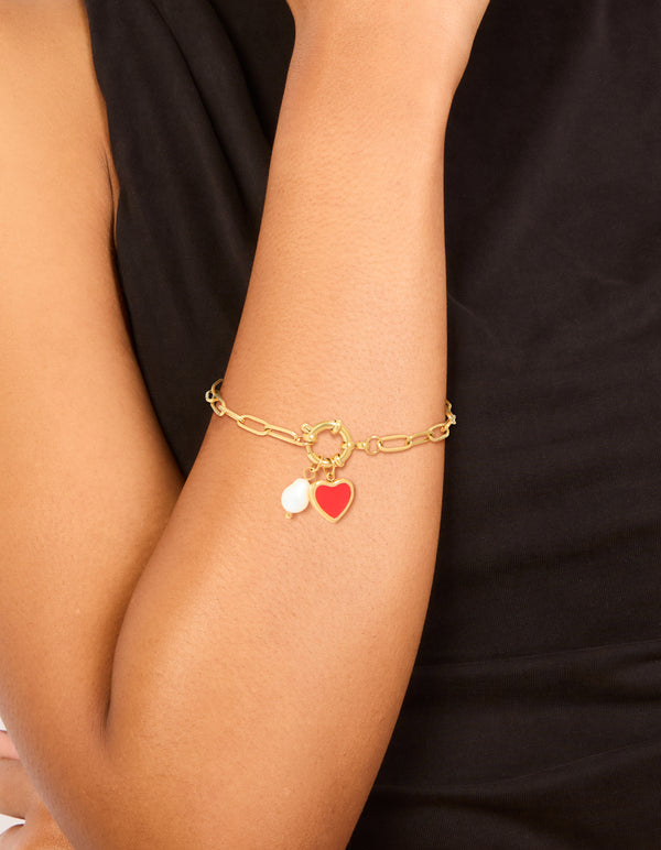 Showcasing a waterproof gold plated stainless steel bracelet with red enamel heart charm and pearl in dainty style on wrist view