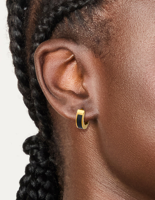 Showcasing small gold plated stainless steel huggie earrings with black enamel inlay and waterproof construction on ear view