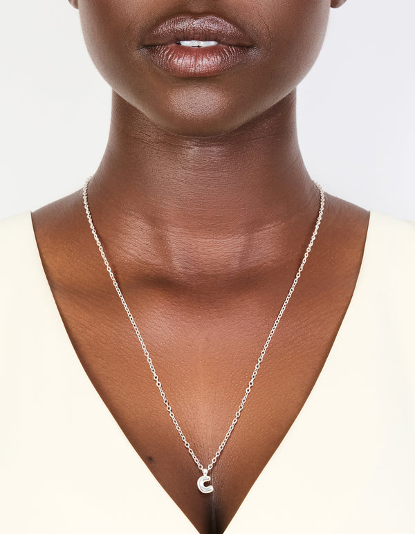 Showcasing a waterproof stainless steel mini bubble letter C necklace with initial pendant in silver on neck view
