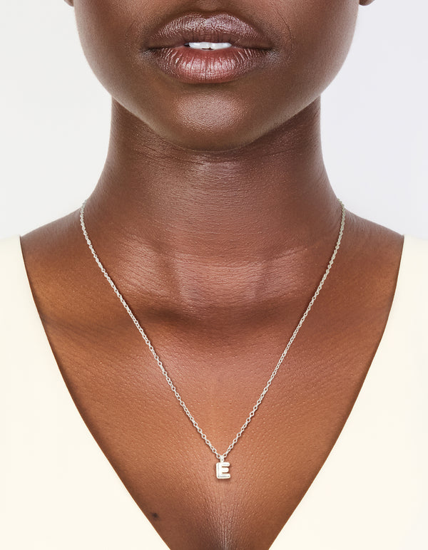 Showcasing a waterproof stainless steel mini bubble letter E necklace with initial pendant in silver on neck view