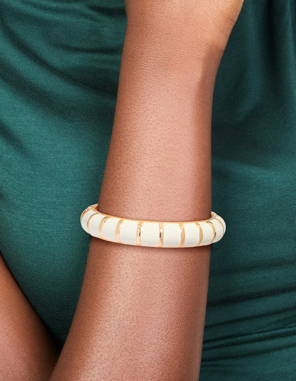 Showcasing a striped enamel bangle in gold and ivory, designed as a comfortable accessory on wrist view