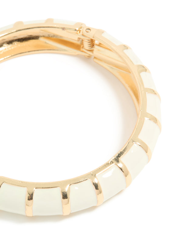 Featuring a striped pattern, this enamel bangle in gold and ivory closure detail view