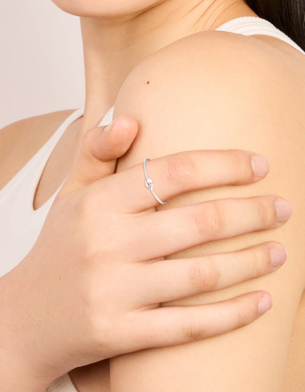 Delicate sterling silver tiny knot ring in dainty style on finger view
