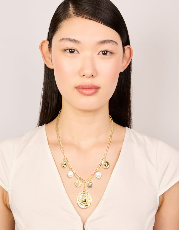 Showcasing gold plated statement circle charm chain necklace with pearl, sun and coin accents on model view