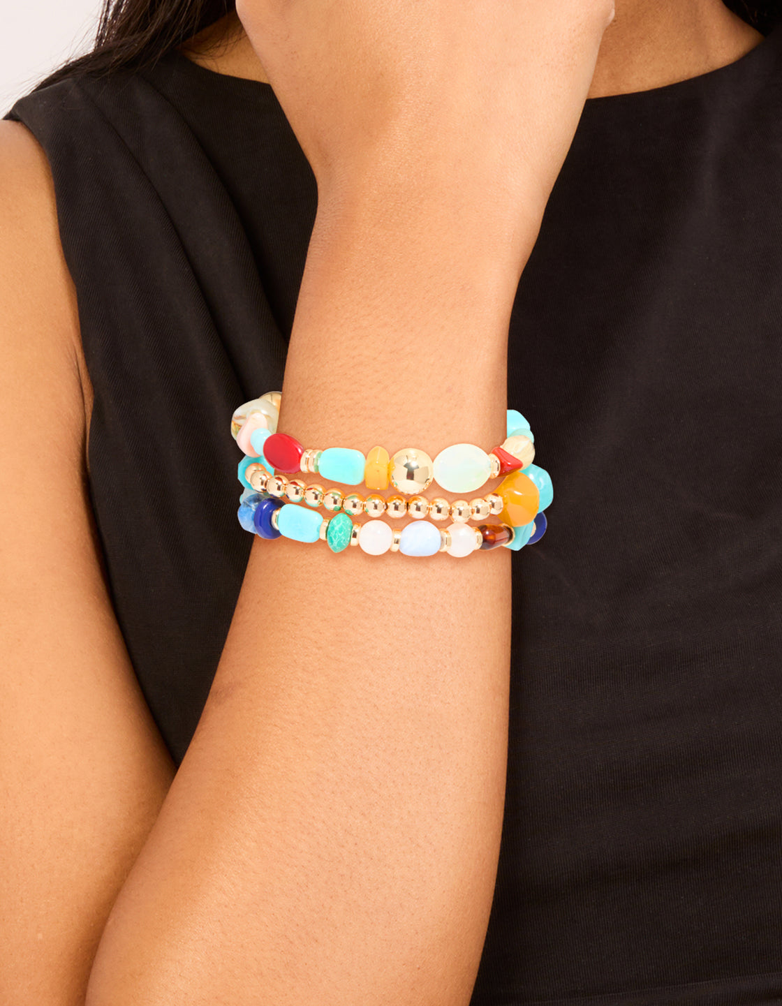 Showcasing multicoloured beaded irregular shape bracelets in a 3-pack with turquoise material and gold accents, blue and white details on wrist view