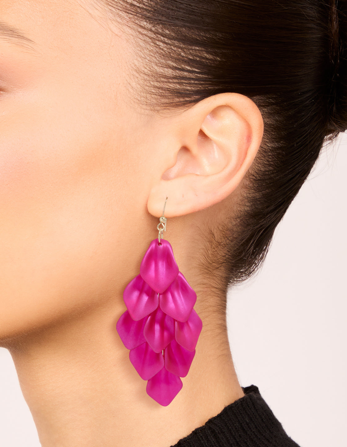 Showcasing fuchsia pink coated metal petal drop earrings with floral design in statement style on ear view