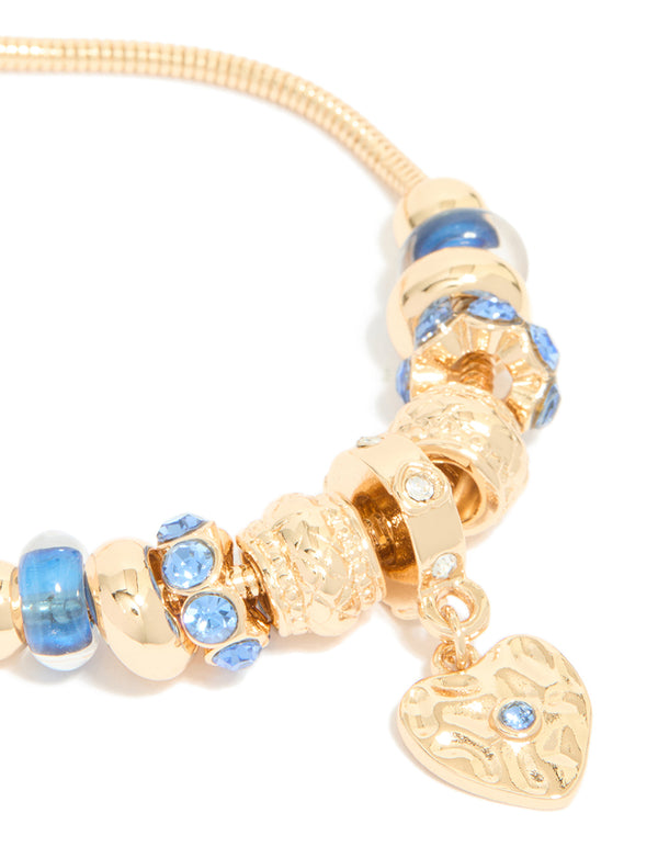 Highlighting a gold blue diamante and molten heart charm toggle bracelet with beaded and balls texture close up view