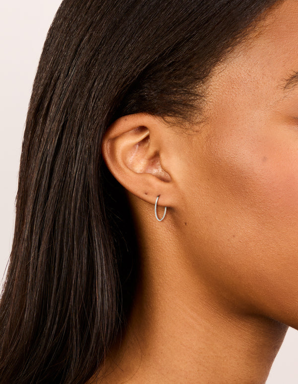 Showcasing fine surgical steel sleeper earrings in silver with hoop closure on ear view