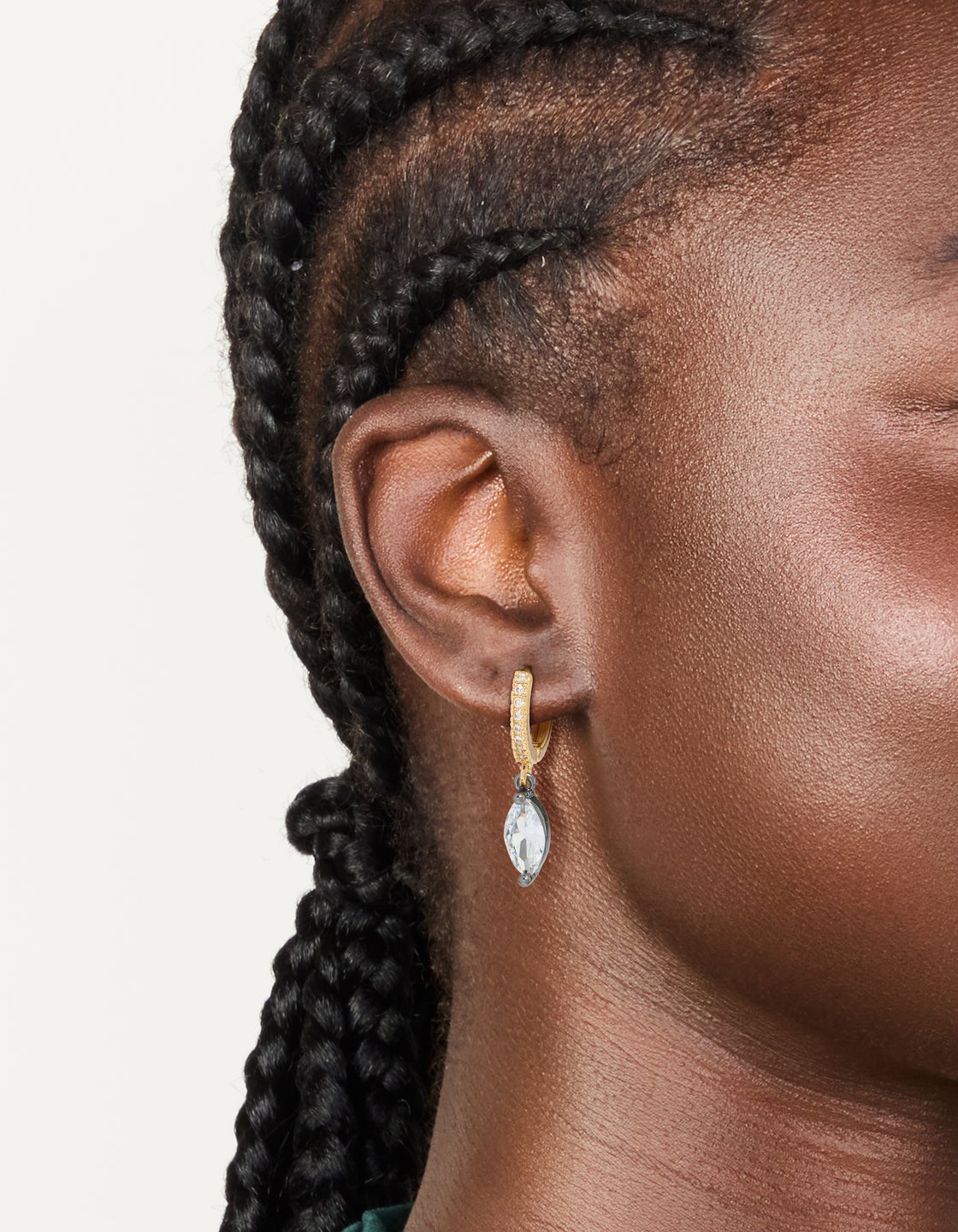 Showcasing mixed metal plated cubic zirconia oval huggie drop earrings in gold, silver, and clear stone on ear view