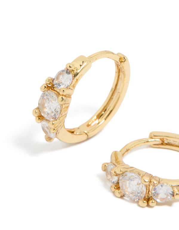 Designed with gold plated mixed sized cubic zirconia mini huggie earrings featuring huggie closure close up view
