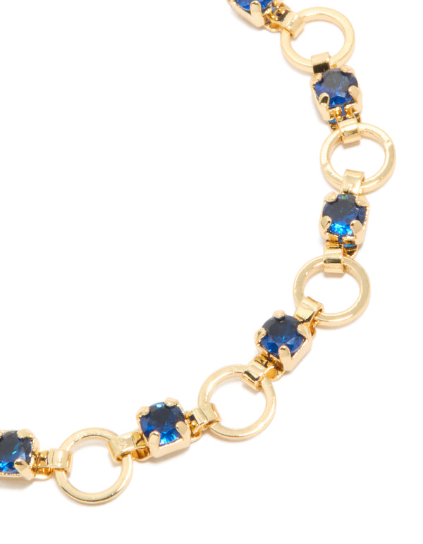 Showcasing a gold plated bracelet with blue cubic zirconia in round cut and alternating link design close up view