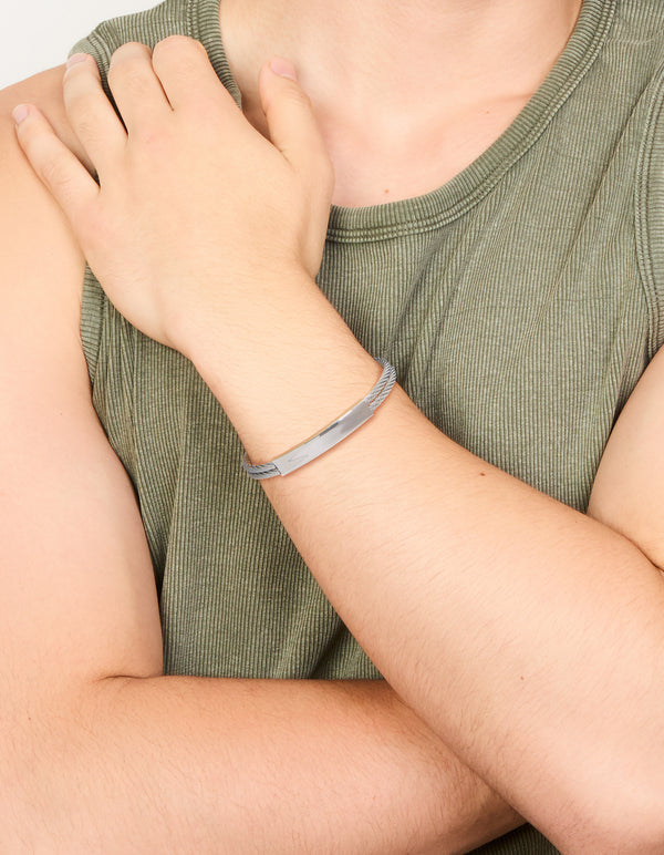Featuring a mens waterproof stainless steel twin wire twisted cuff with bar detailing in silver on wrist view