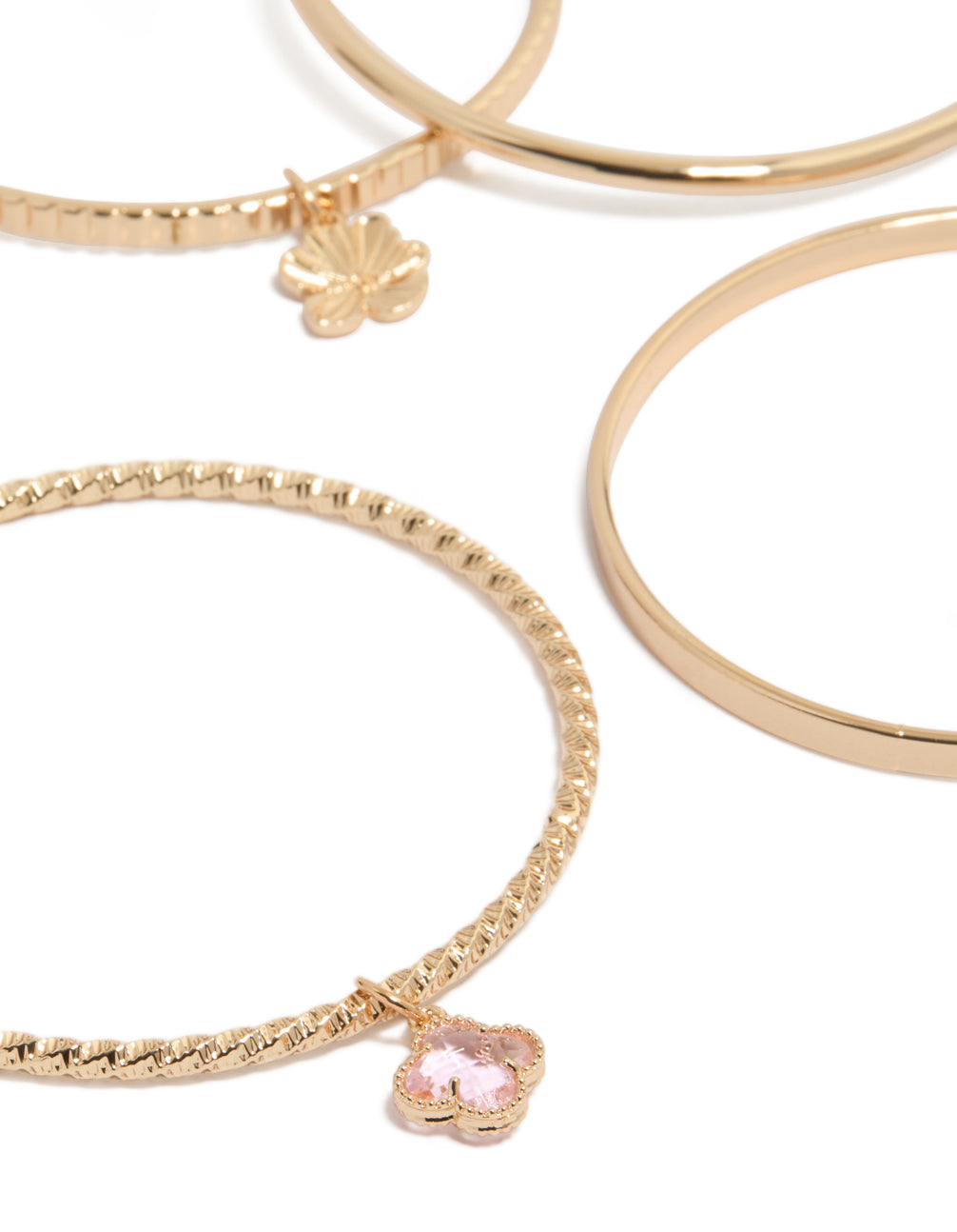 Crafted with celestial sun, floral, and leaf charm bangles in gold with pink accents, close up view
