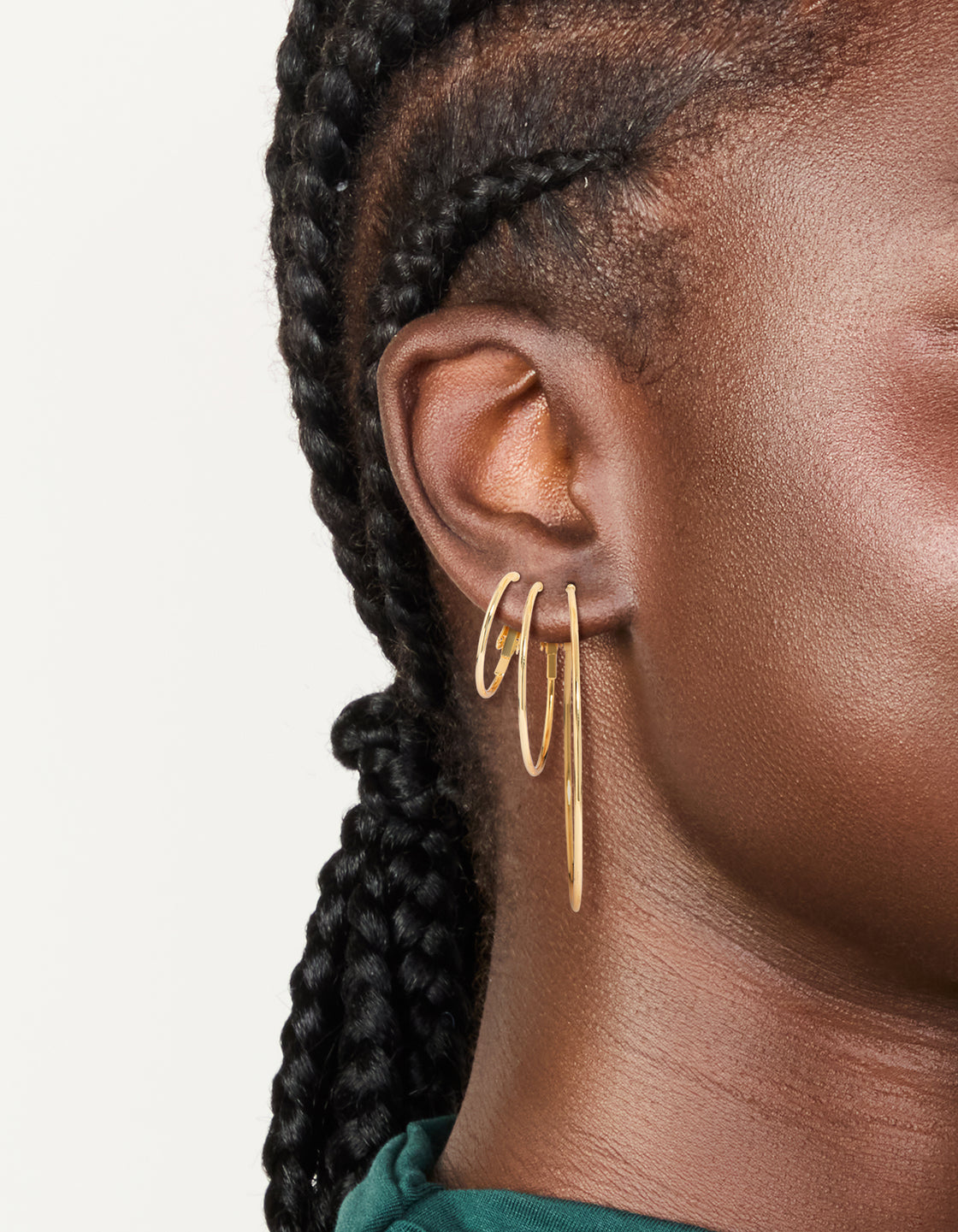 Featuring waterproof gold plated stainless steel extra thin hoop earrings in a 3-pack with closure and gold color on ear view