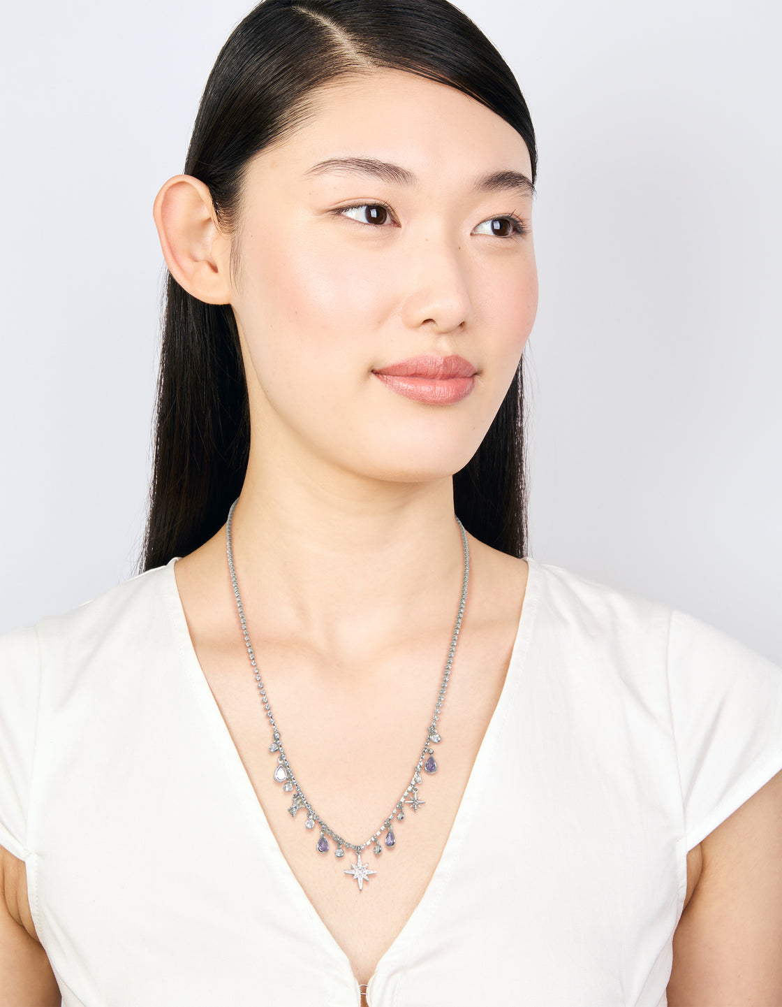 Styled silver lilac cubic zirconia teardrops and celestial star charms necklace with pear shape crystal features on model view