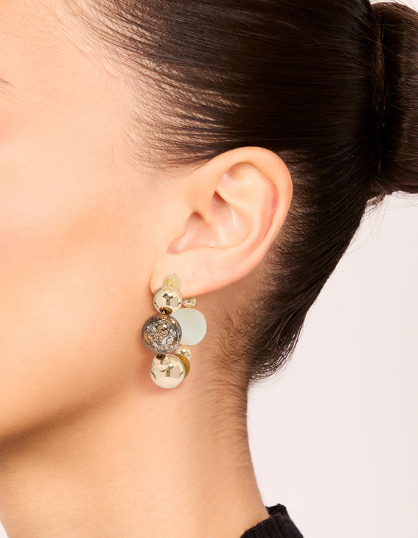 Showcasing chunky beaded ball hoop earrings in gold with neutral tones on ear view