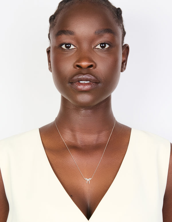 Presenting a sterling silver cubic zirconia bow pendant necklace with dainty on model view