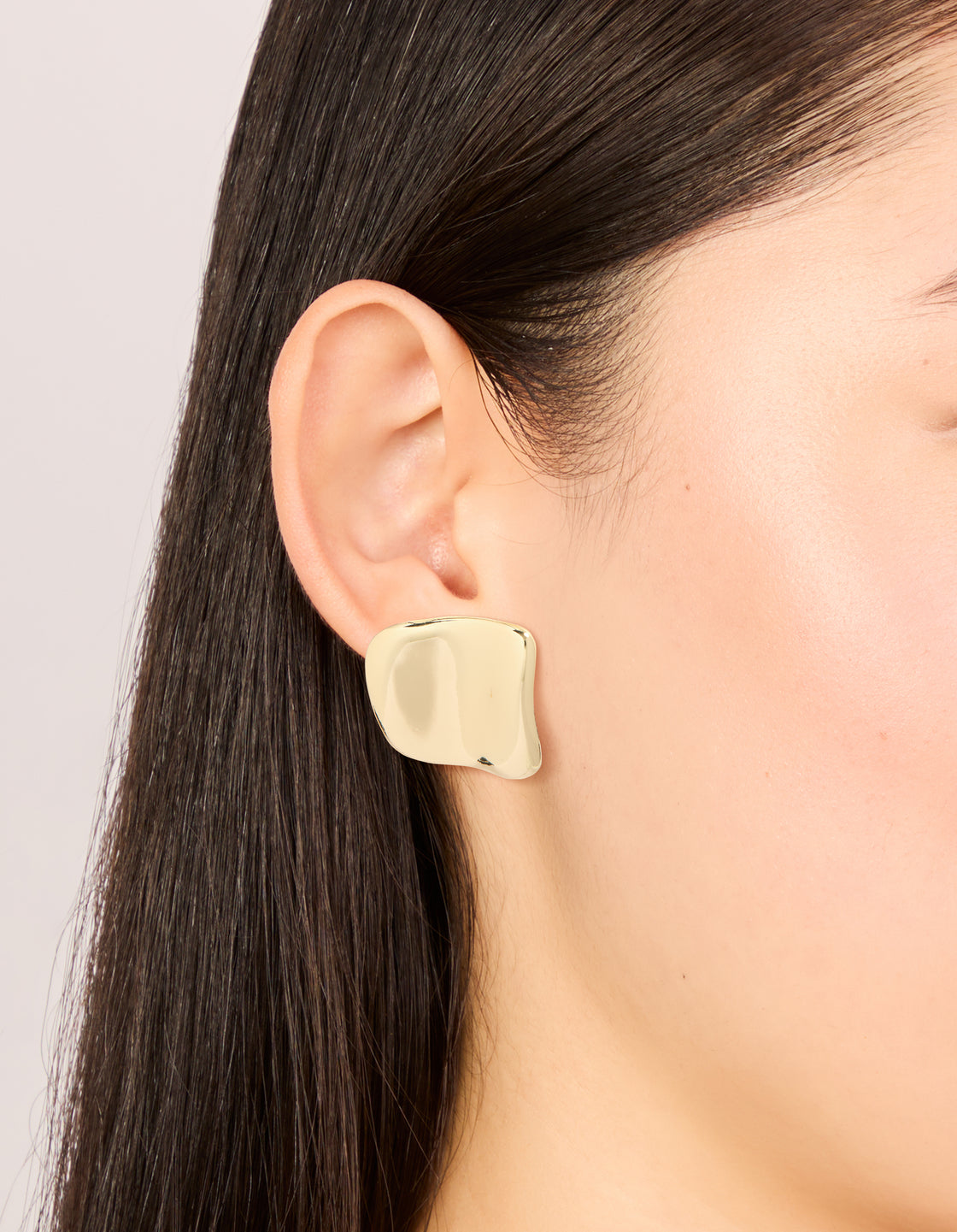 Showcasing gold plated curved square stud earrings on ear view
