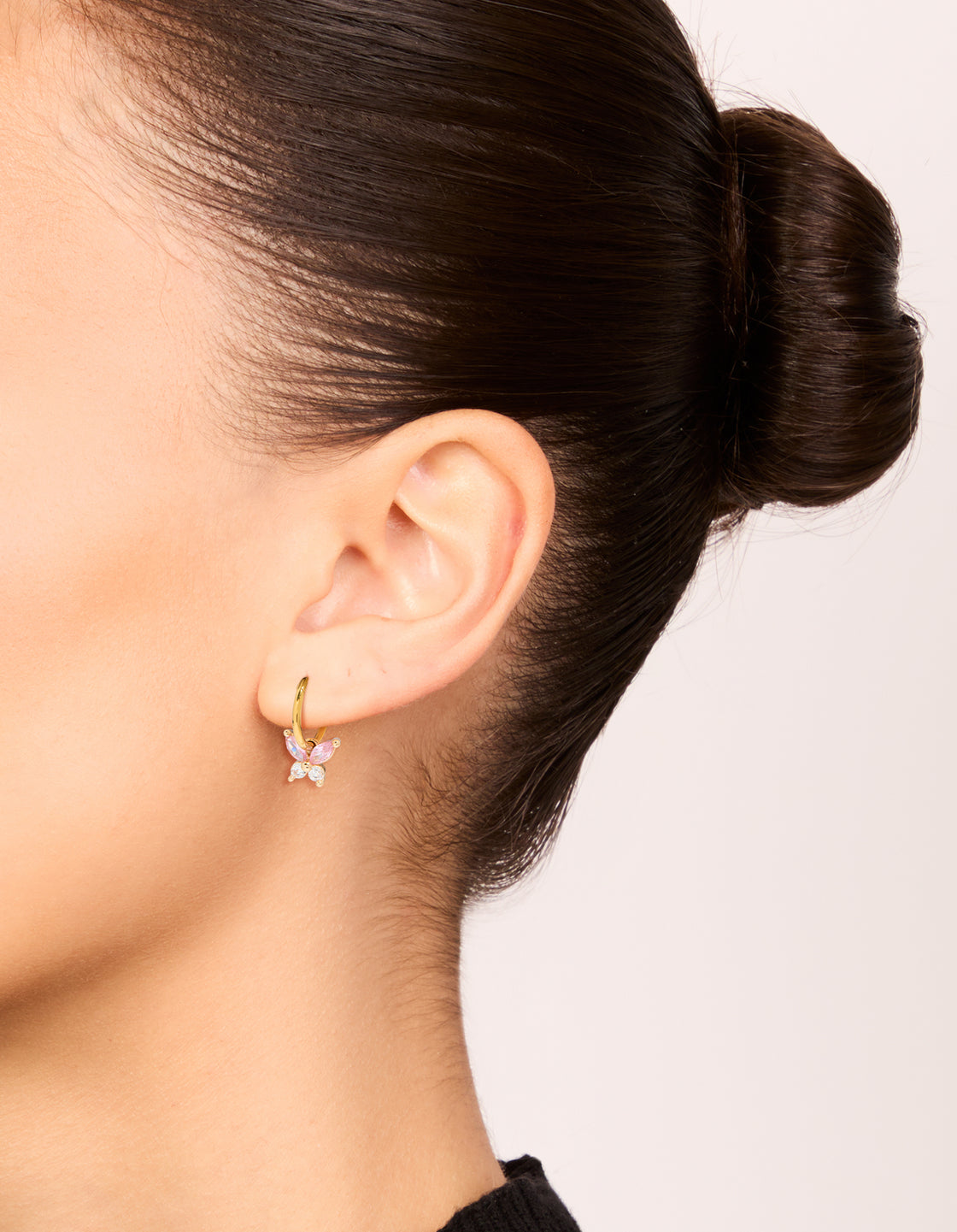 Stylish gold plated surgical steel butterfly sleeper earrings with pink cubic zirconia on ear view