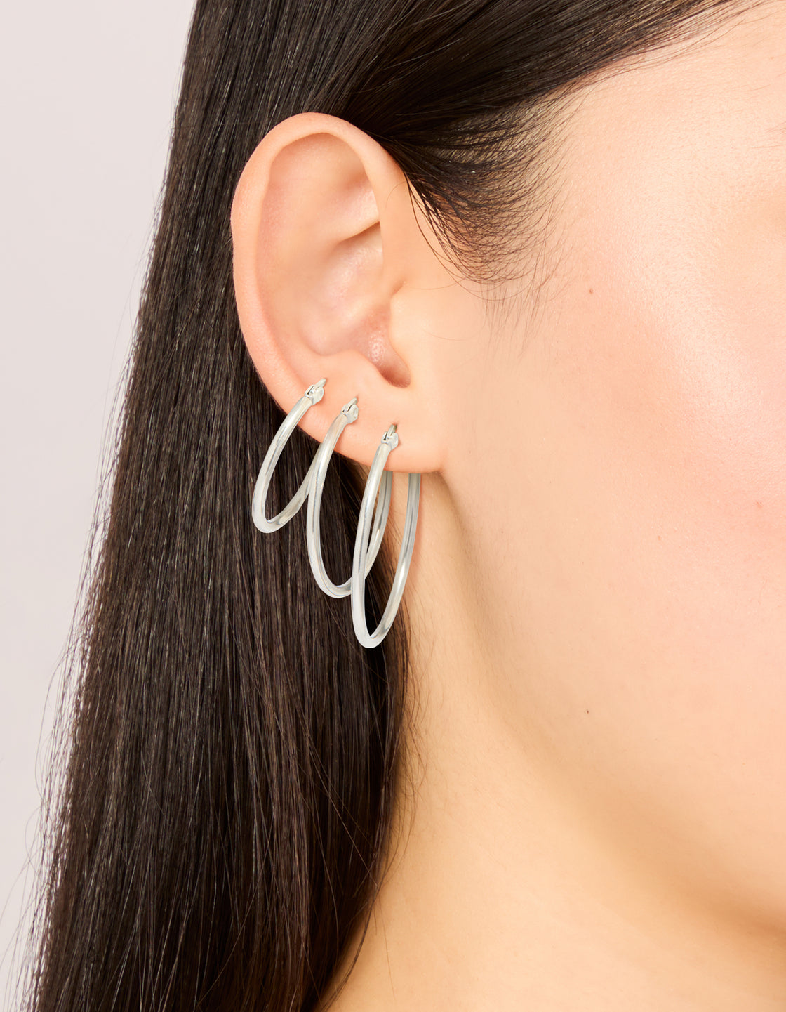 Showcasing waterproof stainless steel large thin mix hoop earrings in silver 3-pack on ear view