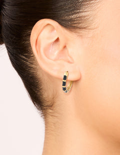 Showcasing waterproof stainless steel huggie earrings with bamboo-inspired segments in gold and black enamel on ear view