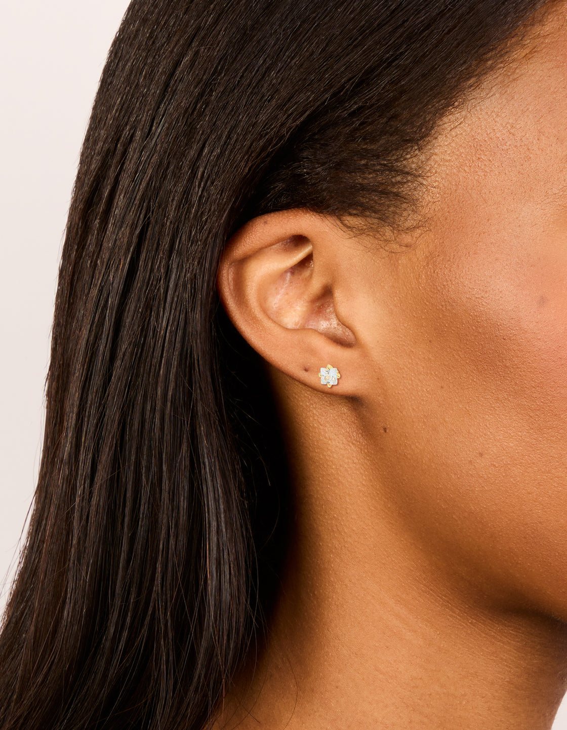 Showcasing studs with gold plated surgical steel and cubic zirconia having flat back with clear stone accents on ear view