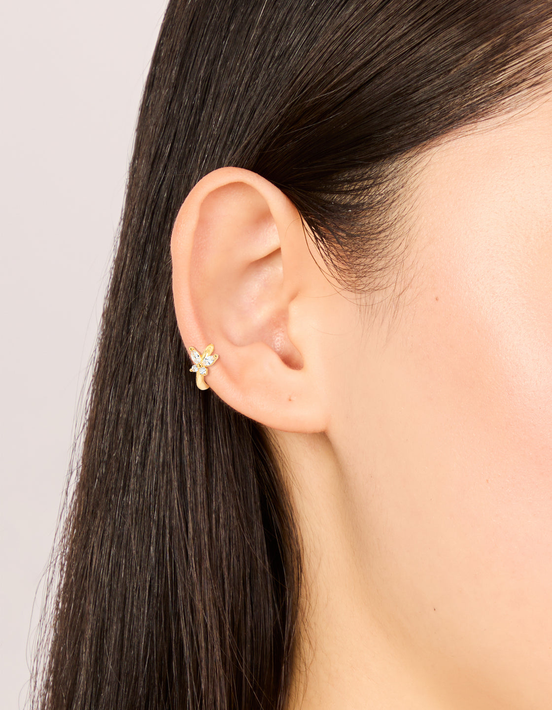 Showcasing a butterfly clicker ring crafted from surgical steel and clear cubic zirconia in gold and dainty styling with hoop closure on ear view