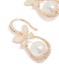 Featuring white pearl center surrounded by cubic zirconia in oval cut, butterfly charm hook earrings with rose gold plated finish close up view - link has visual effect only