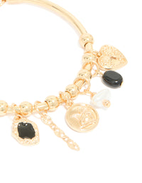 A gold heart and black stone charm bracelet designed with balls, coin and pearl elements close up view - link has visual effect only
