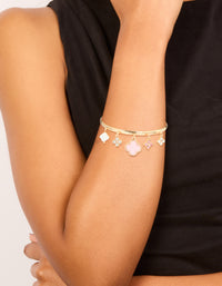 Showcasing a gold pink flowers charm toggle bangle with floral quatrefoil details in statement style on wrist view - link has visual effect only