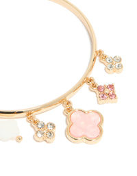 Highlighting a gold pink flowers charm toggle bangle with floral quatrefoil charms and statement design close up view - link has visual effect only