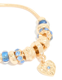 Highlighting a gold blue diamante and molten heart charm toggle bracelet with beaded and balls texture close up view - link has visual effect only