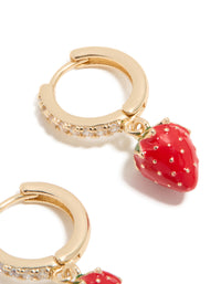 Designed with gold cubic zirconia, these strawberry huggie earrings showcase fruit elements in red, green, and white on ear view - link has visual effect only