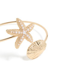 Showcasing a gold shell and pearl starfish arm cuff with ocean-inspired close up view - link has visual effect only