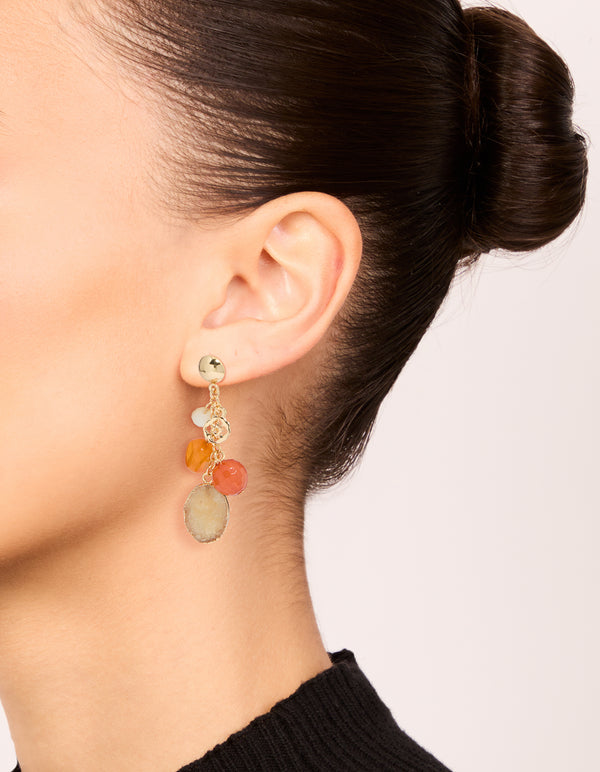 Crafted from gold beaded hoop and drop earrings 3-pack featuring charms with hoop closure in orange, tan, and coral tones on ear view