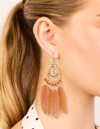 Crafted from gold featuring beads and feathers in coral, these statement drop earrings shown in on ear view - link has visual effect only