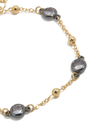 Bracelet featuring mixed metal, cubic zirconia stones set in grey bezels alternating with gold plated balls on delicate chain close up view - link has visual effect only